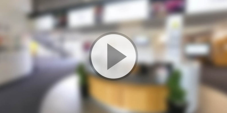 Blurred image of the Tamworth Sixth Form Reception area overlaid with a circular play button