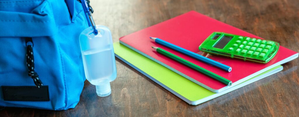 Sanitizer gel on a blue color school bag wooden background