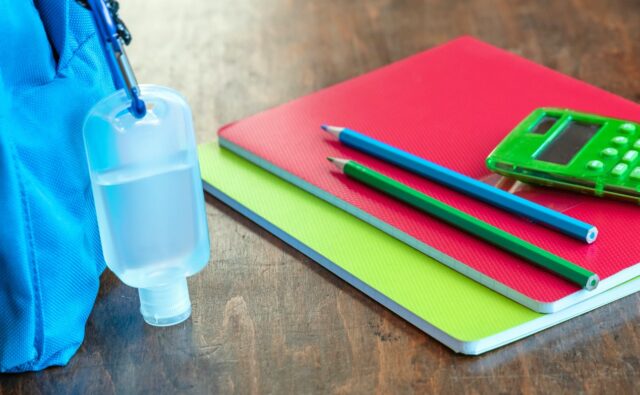 Sanitizer gel on a blue color school bag wooden background